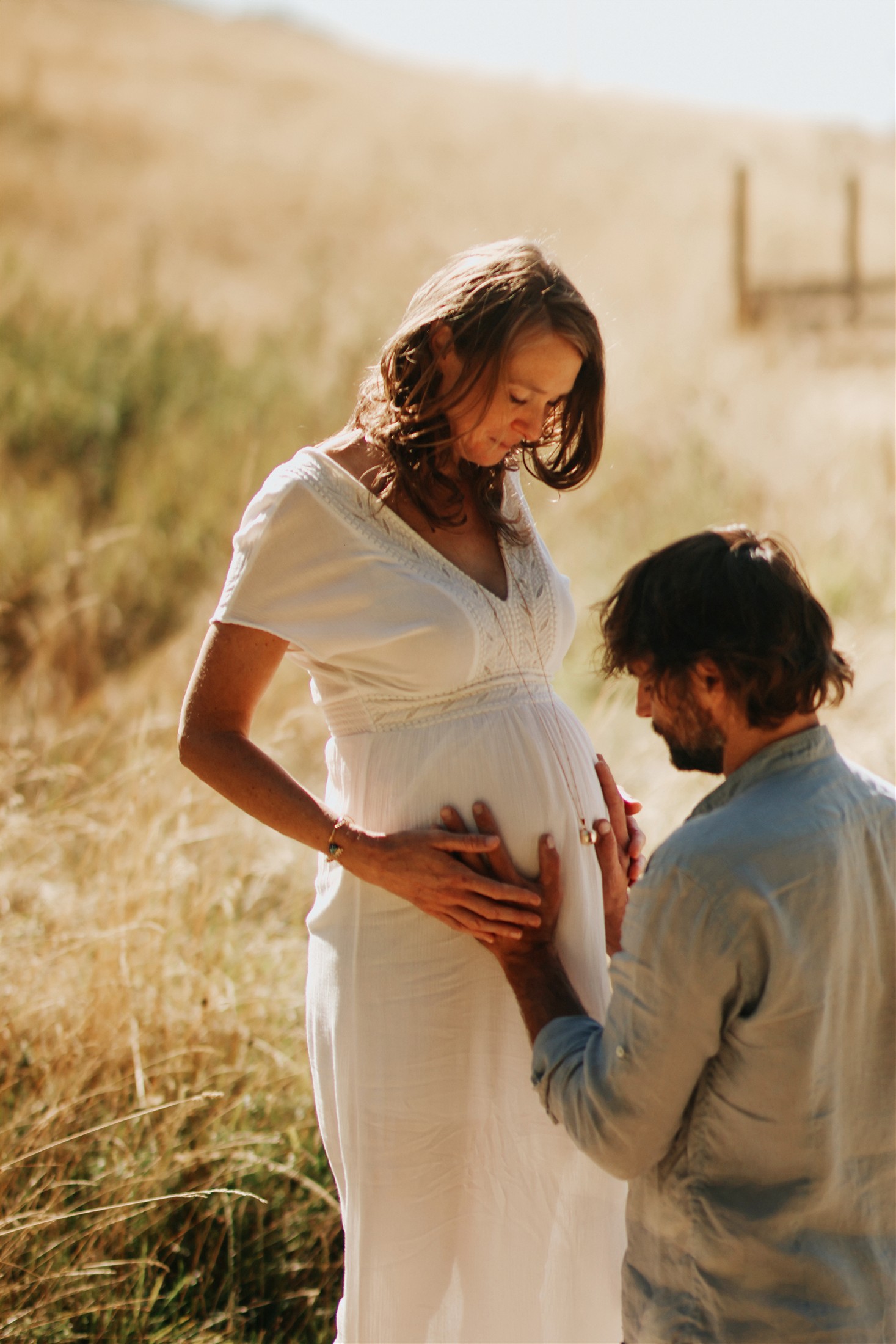 Couple attendant un bébé dans un champ au soleil